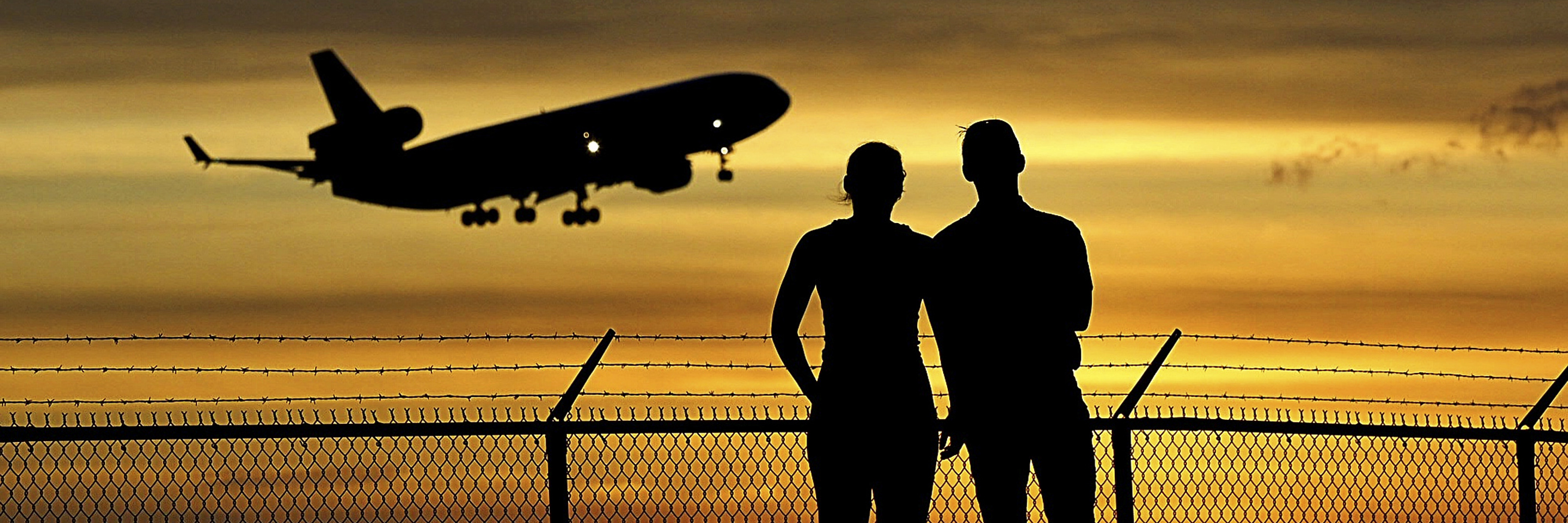 Aircraft landing at Sunset with onlooking couple